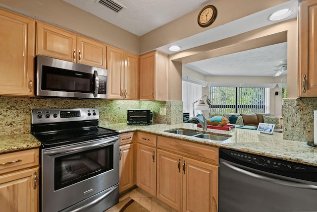 kitchen with visible vents, a sink, light stone counters, tasteful backsplash, and stainless steel appliances