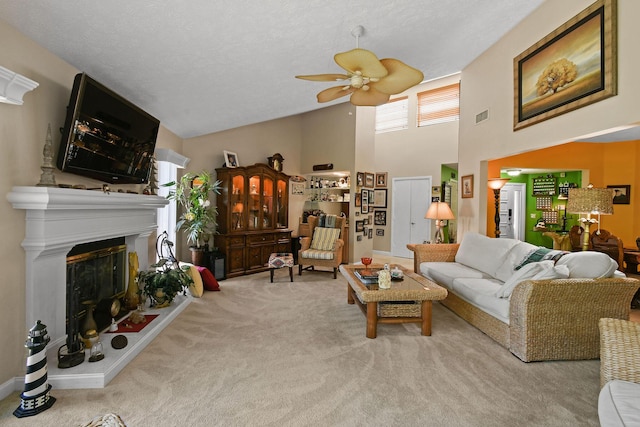 living area featuring visible vents, carpet flooring, a glass covered fireplace, high vaulted ceiling, and a ceiling fan