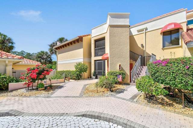 view of front of property with a tiled roof, stucco siding, and stairway