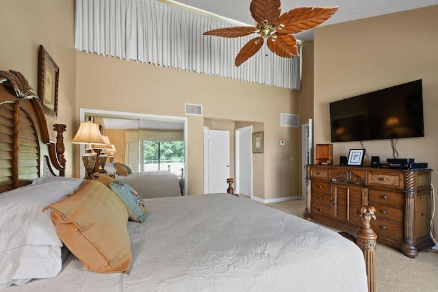 bedroom featuring carpet, visible vents, baseboards, a closet, and a towering ceiling