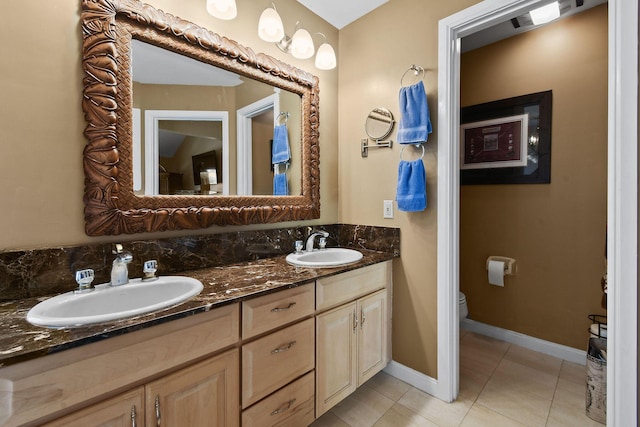 bathroom with a sink, toilet, double vanity, and tile patterned floors