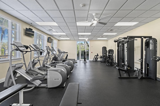 exercise room featuring a drop ceiling, a ceiling fan, and baseboards