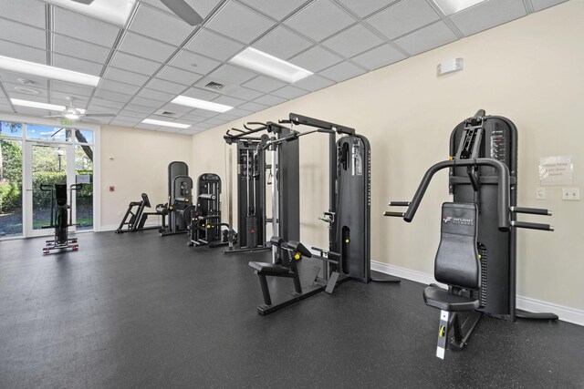 workout area featuring baseboards, a paneled ceiling, and visible vents