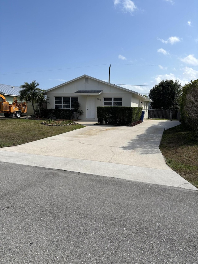 view of front of home with concrete driveway, a front yard, and fence