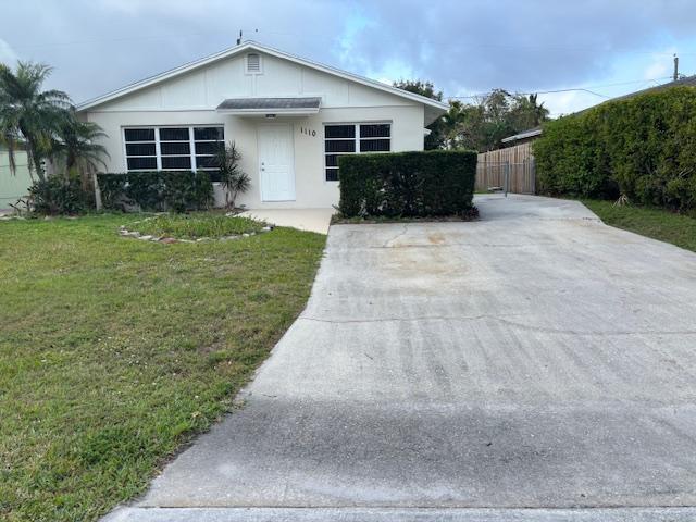 ranch-style house featuring fence and a front lawn