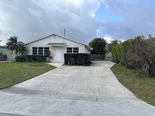 view of front of house with stucco siding, concrete driveway, a front yard, and fence