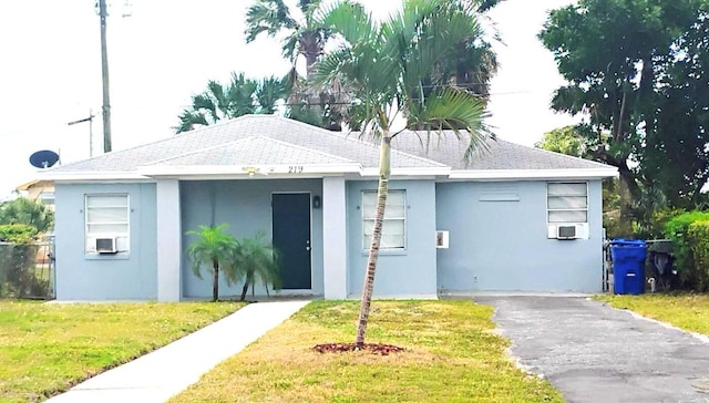 view of front of property featuring stucco siding, cooling unit, and a front yard