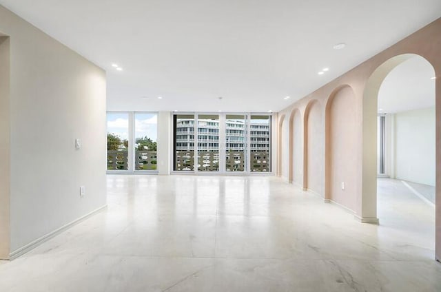 spare room featuring expansive windows, arched walkways, and recessed lighting