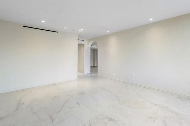 spare room featuring arched walkways, marble finish floor, and recessed lighting