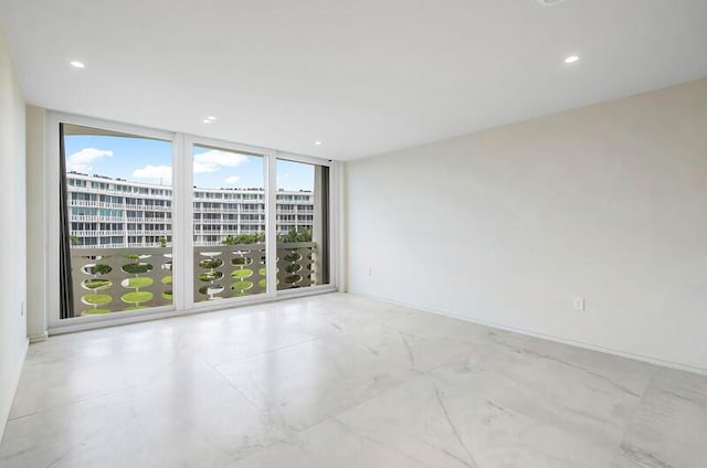 unfurnished room featuring marble finish floor, a wall of windows, and recessed lighting