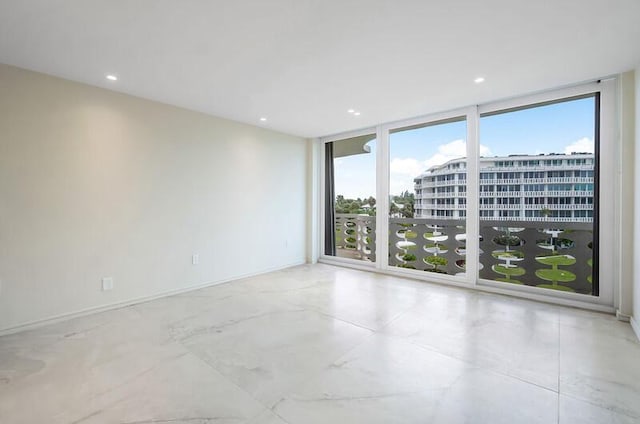 spare room with a wall of windows, recessed lighting, and baseboards