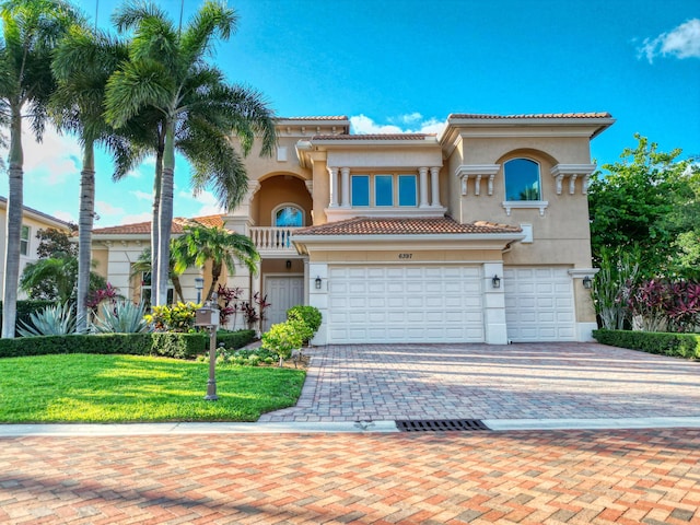 mediterranean / spanish-style house featuring decorative driveway, a tiled roof, an attached garage, and stucco siding