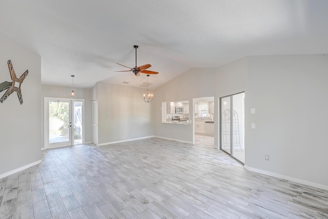 unfurnished living room featuring light wood-style flooring, ceiling fan with notable chandelier, baseboards, and vaulted ceiling