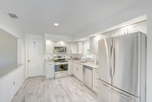 kitchen with decorative backsplash, stainless steel appliances, wood finish floors, and light stone countertops