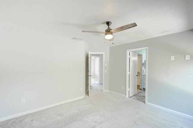 unfurnished bedroom featuring visible vents, light carpet, ensuite bathroom, a textured ceiling, and baseboards