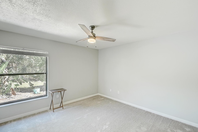 carpeted spare room featuring ceiling fan, a textured ceiling, and baseboards