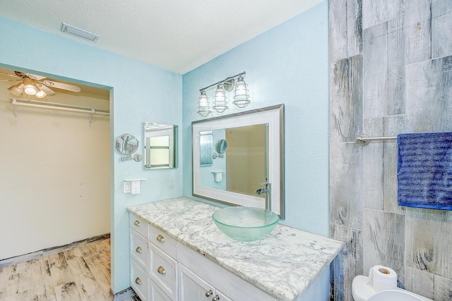 full bath with visible vents, a walk in closet, a ceiling fan, wood finished floors, and vanity