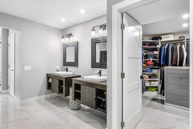 bathroom with marble finish floor, two vanities, and a sink