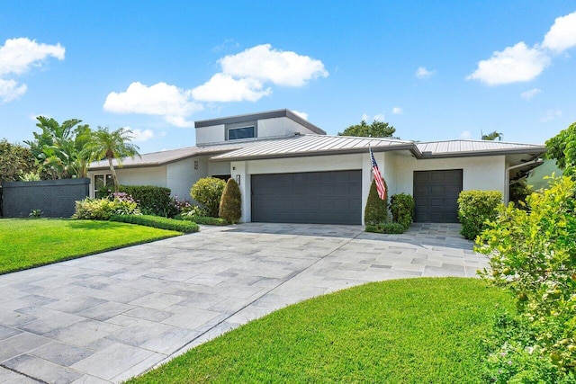 mid-century modern home with a standing seam roof, metal roof, a garage, driveway, and a front lawn