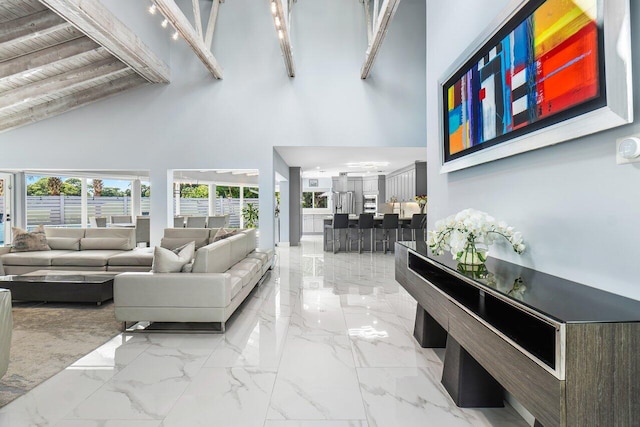 living room with marble finish floor, a high ceiling, and beam ceiling