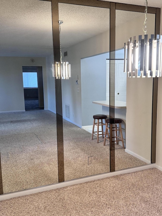 dining area with a textured ceiling, carpet flooring, visible vents, and a chandelier