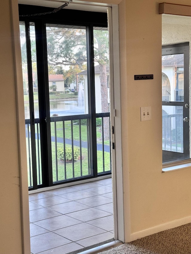 doorway to outside featuring tile patterned floors, plenty of natural light, baseboards, and a water view