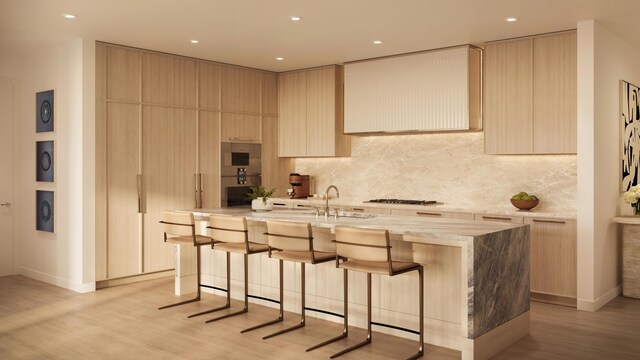 kitchen with a kitchen breakfast bar, light wood finished floors, a kitchen island with sink, and tasteful backsplash