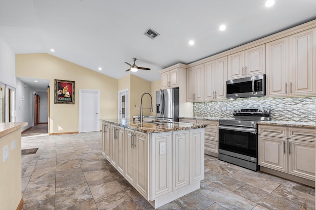 kitchen featuring cream cabinetry, a center island with sink, visible vents, appliances with stainless steel finishes, and vaulted ceiling