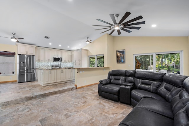 living area featuring a ceiling fan, visible vents, vaulted ceiling, and baseboards