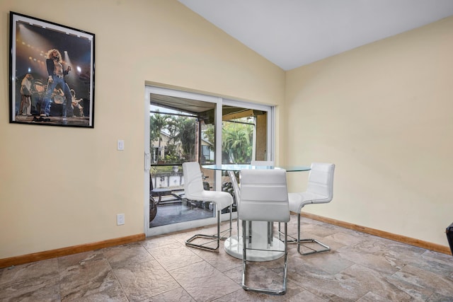 dining area with lofted ceiling, stone finish floor, and baseboards