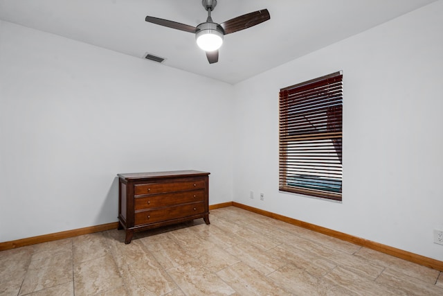 empty room featuring ceiling fan, visible vents, and baseboards