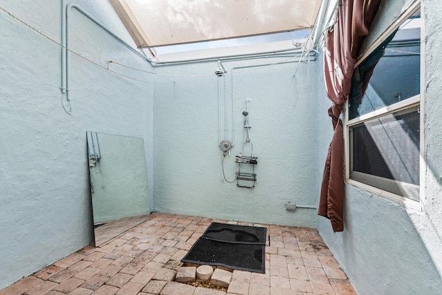 bathroom with brick floor, a skylight, and a textured wall