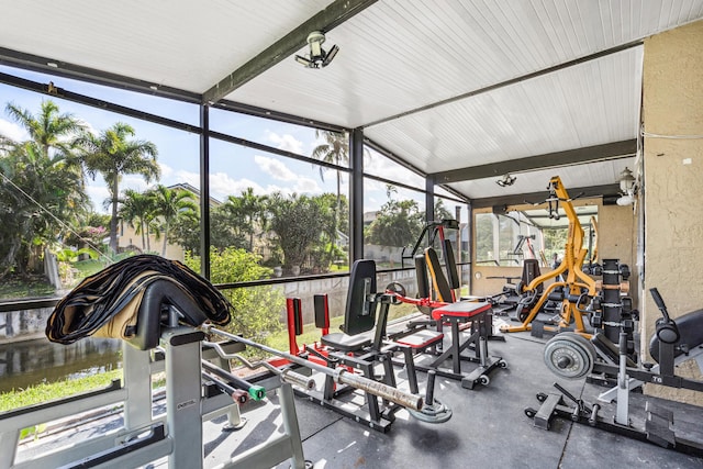 exercise room with vaulted ceiling, a textured wall, and a wall of windows