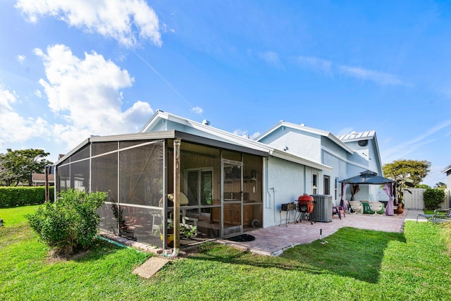 rear view of house with a lawn, fence, central air condition unit, a patio area, and stucco siding