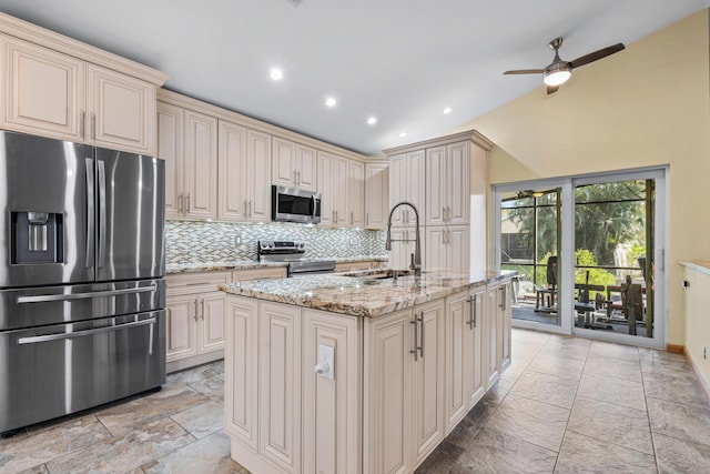 kitchen featuring light stone counters, decorative backsplash, cream cabinets, appliances with stainless steel finishes, and a sink