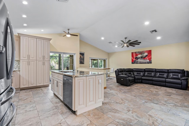 kitchen with visible vents, open floor plan, cream cabinetry, appliances with stainless steel finishes, and light stone countertops