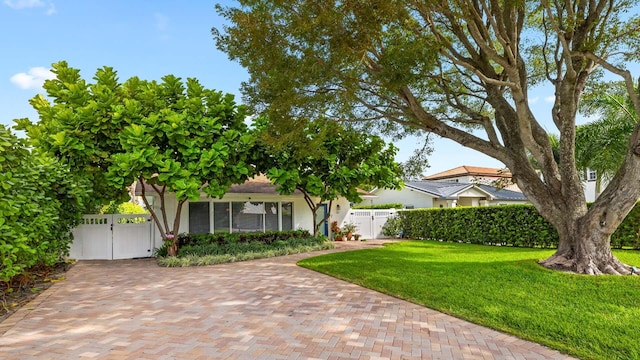 view of property hidden behind natural elements featuring a gate, fence, a front lawn, and stucco siding