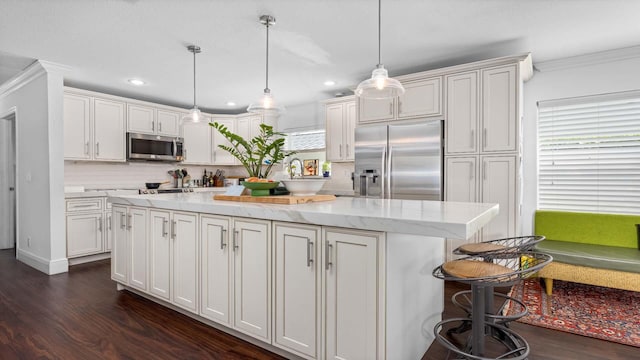 kitchen featuring decorative backsplash, white cabinets, appliances with stainless steel finishes, dark wood-style flooring, and a center island