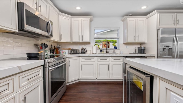 kitchen featuring beverage cooler, dark wood-style floors, a sink, stainless steel appliances, and backsplash