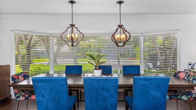 dining area with ornamental molding, a notable chandelier, and wood finished floors