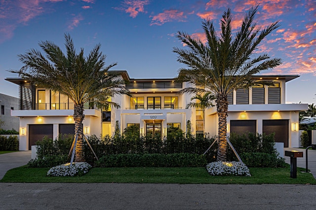 view of front facade featuring an attached garage, a balcony, driveway, and stucco siding