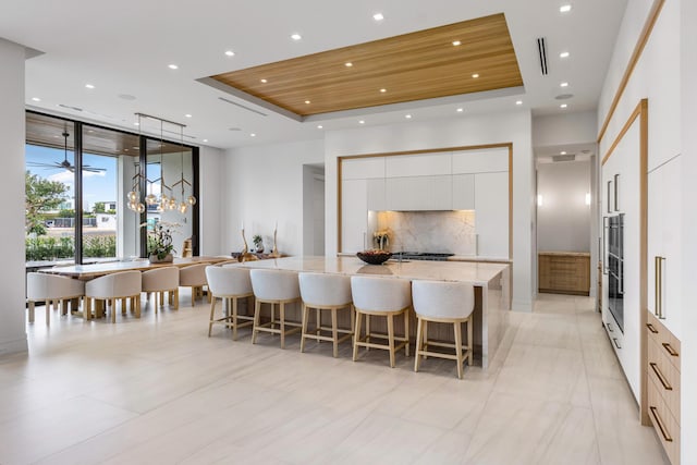 kitchen with a kitchen breakfast bar, white cabinets, a large island, a tray ceiling, and modern cabinets