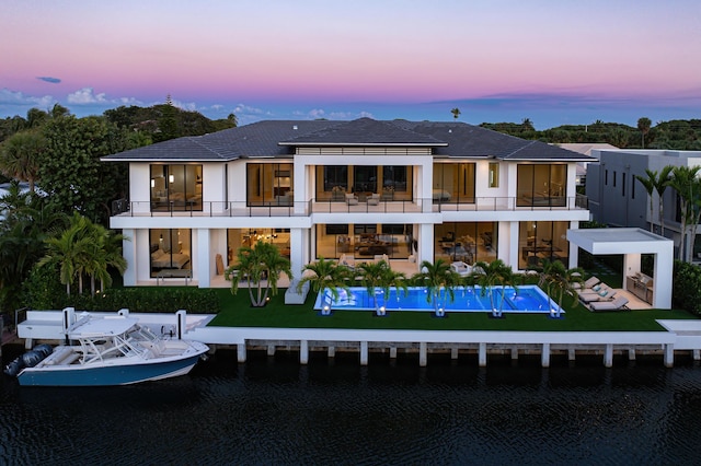 back of property at dusk featuring an outdoor hangout area, a patio, and a balcony