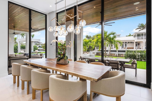 dining room featuring a wall of windows, tile patterned floors, a healthy amount of sunlight, and a ceiling fan