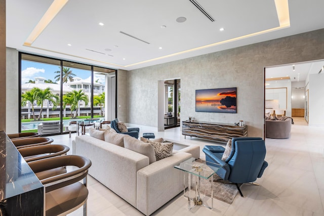 living room with a tray ceiling, a wall of windows, and recessed lighting