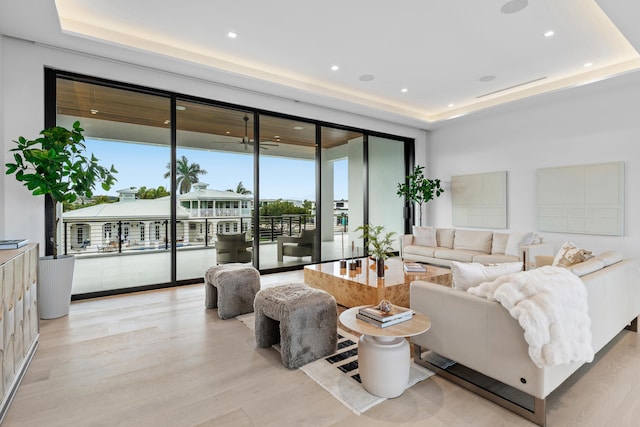 living area featuring light wood-style flooring, a tray ceiling, and recessed lighting