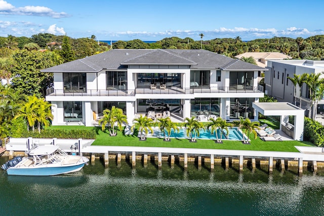 back of property featuring a balcony, a water view, a sunroom, a yard, and a patio area