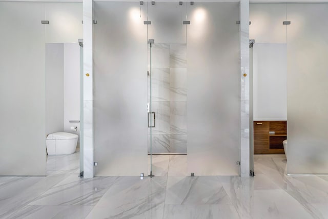 full bathroom featuring marble finish floor, a shower stall, and toilet