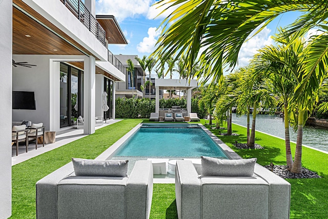 outdoor pool featuring a patio area, a yard, outdoor lounge area, and a water view