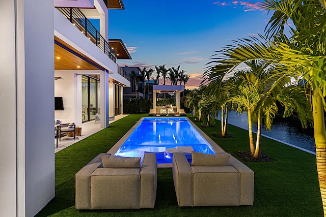 pool at dusk featuring a lawn, a patio area, and an outdoor pool